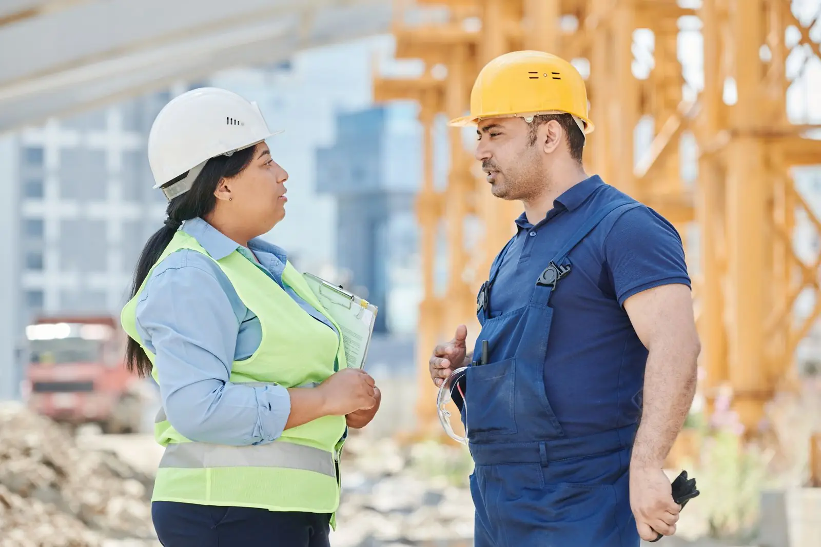 Two engineers in hard hats talking at a construction site